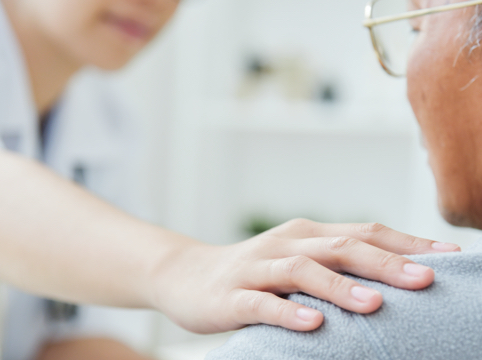 Healthcare professional touching a patient’s shoulder in sign of support and empathy